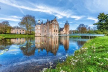 Menkemaborg met torens, slotgracht en brug in een groen landgoed