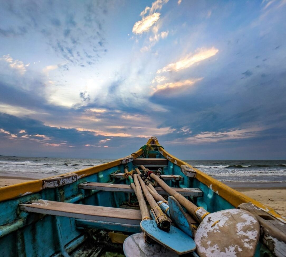 Oude houten roeiboot op een woelige zee onder een bewolkte avondlucht
